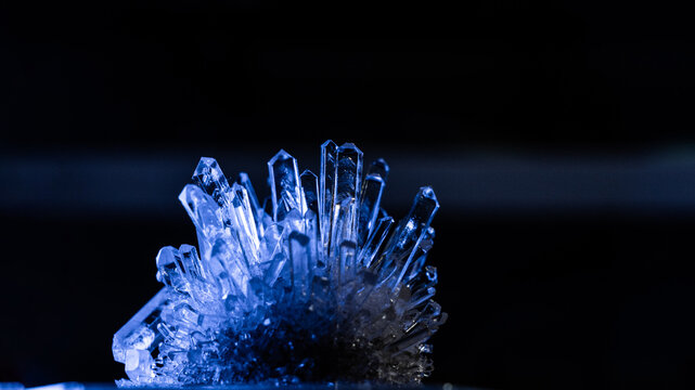 A mysterious, genuine crystal. The grown crystal rotates on an illuminated turntable. A scientific experiment and chemical study. A beautiful background or screensaver. Blue.