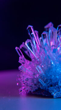 A mysterious, magical, genuine crystal. The grown crystal rotates on an illuminated turntable. A scientific experiment and chemical study. A beautiful background or screensaver. Blue and pink.