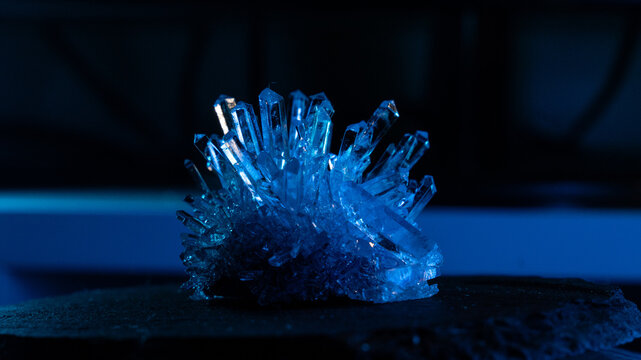 A mysterious, genuine crystal. The grown crystal rotates on an illuminated turntable. A scientific experiment and chemical study. A beautiful background or screensaver. Blue.