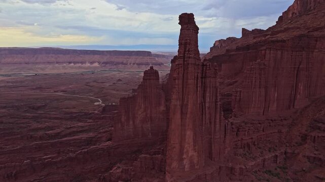 High drone perspective reveals sweeping red rock valleys and rugged mudstone spires glowing under warm sunset skies in Utah