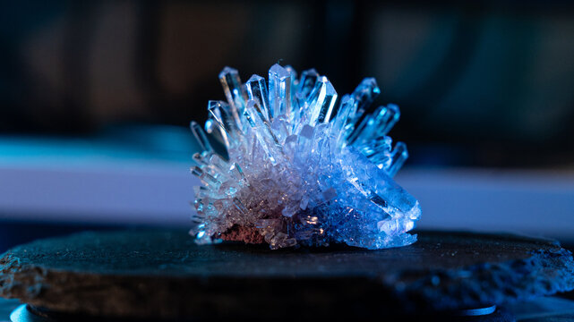 A mysterious, genuine crystal. The grown crystal rotates on an illuminated turntable. A scientific experiment and chemical study. A beautiful background or screensaver. Blue.
