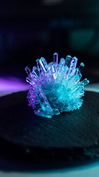 A mysterious, magical, genuine crystal. The grown crystal rotates on a turntable illuminated by full-spectrum RGB lighting. A scientific experiment and chemical study. A beautiful background