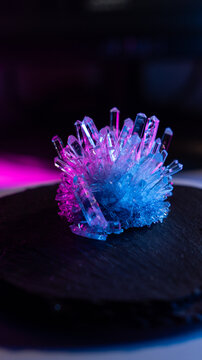 A mysterious, magical, genuine crystal. The grown crystal rotates on an illuminated turntable. A scientific experiment and chemical study. A beautiful background or screensaver. Blue and pink.