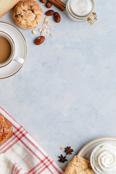 Cozy breakfast flat lay with coffee, cookies, pastries, spices and cream arranged around a large central copy space