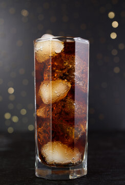 Misted cool glass with a glass of Coke, Pepsi, rum, alcohol ice cubes on a black background