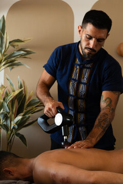 Professional Therapist Using Massage Gun for Muscle Recovery