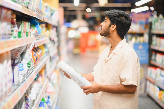 Indian man shopping household chemicals in supermarket aisle