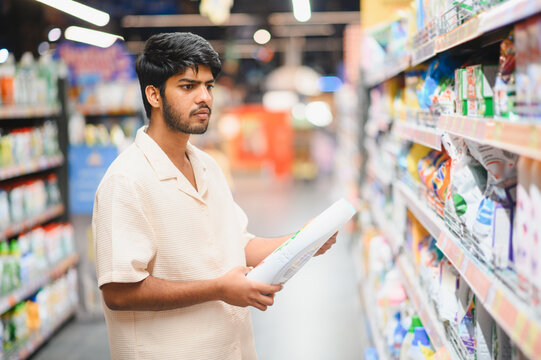Indian man shopping household chemicals in supermarket aisle
