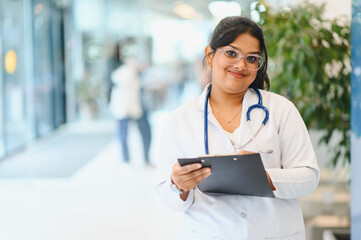 Indian female doctor smiling holding clipboard in hospital