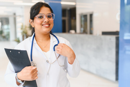 Indian female doctor smiling holding clipboard in hospital lobby