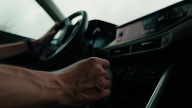Driver's hands on car gearshift and steering wheel