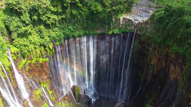 Aerial Pull Back Shot of Tumpak Sewu Waterfall with Rainbow