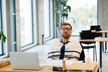 Obraz premium Businessman tied at office desk experiencing stress