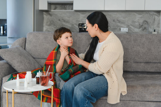 Mother comforting sick child with sore throat at home