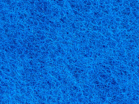 A close-up view of the fibrous abrasive pad side of a bright blue cleaning sponge showing interconnected synthetic fibers.