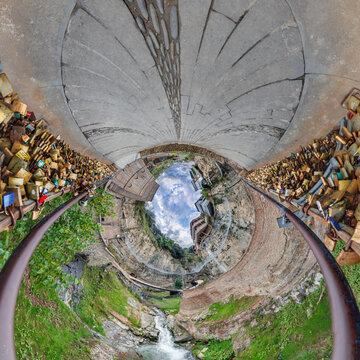 creative tiny planet photo of a rural landscape with dirt road, green fields, and cloudy sky forming a circular world.