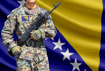 Obraz premium Bosnia and Herzegovina flag with soldier holding assault rifle