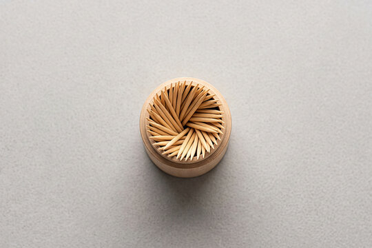 Top view of bamboo wooden toothpicks in a round holder on a grey background