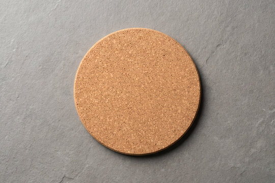 Blank round cork drink coaster top view on a grey stone background