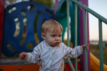 Toddler stands on playground platform near blue wall and metal bar © WoodHunt