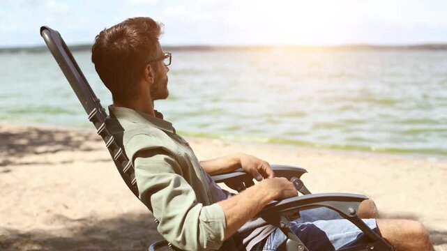 A man is sitting in a beach chair by the water