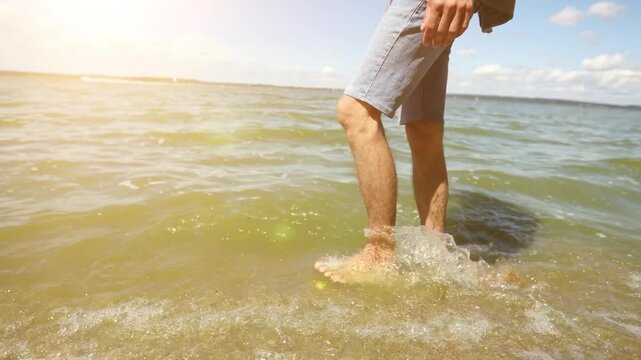 A man is walking on the beach with his feet in the water