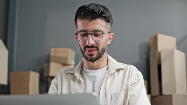 Young man wears glasses, focused on laptop