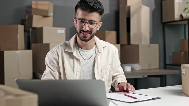 Young man smiles while working at a desk