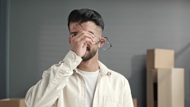 Young man with glasses and beard stands calmly