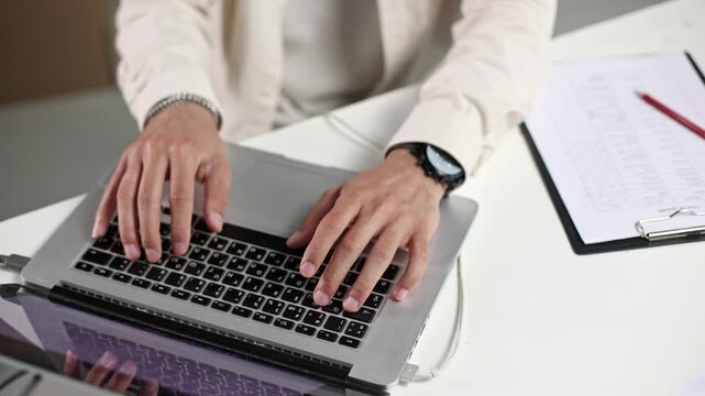 Focused hands type on laptop keyboard