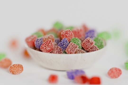 3d sugary gummy candies in a bowl, white background