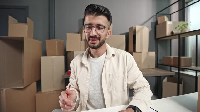 Man sits at desk, holding red marker