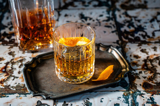 Bourbon in rocks glasses with a decanter with an orange twist 