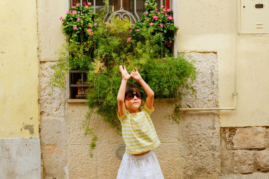 Young Girl Wearing Sunglasses Raising Arms Outdoors in Summer