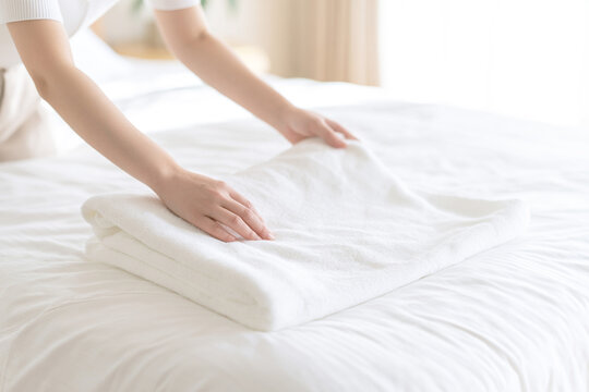 ベッドの上で白いタオルを丁寧に整える女性
