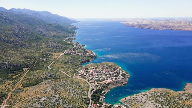 Aerial view of small villages, winding road and blue sea along a rocky coast