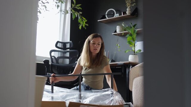 Woman unpacking metal shelf frame for DIY furniture assembly at home