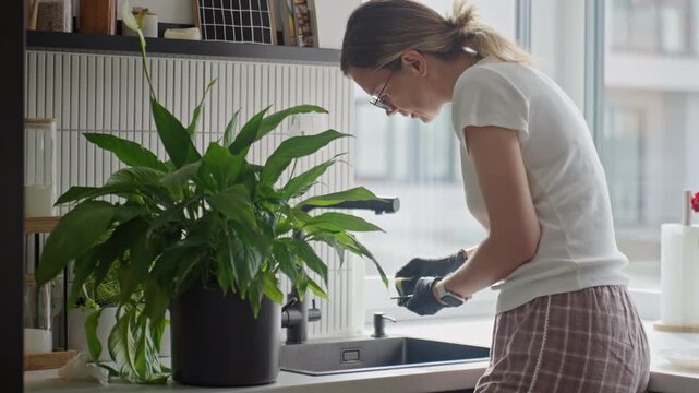 Woman washing dishes at kitchen sink at home