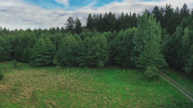 Panorama z wysokości wykonana przy użyciu zmieniającego położenie drona. Pofałdowany teren na Przedg&oacute;rzu Sudeckim, pokryty łąkami, polami uprawnymi i lasami.  