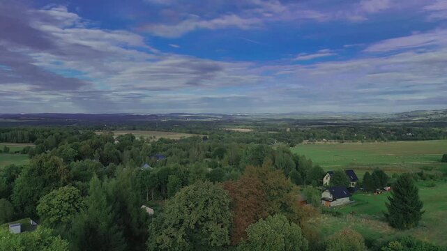 Panorama z wysokości wykonana przy użyciu zmieniającego położenie drona. Pofałdowany teren na Przedg&oacute;rzu Sudeckim, pokryty łąkami, polami uprawnymi i lasami.  