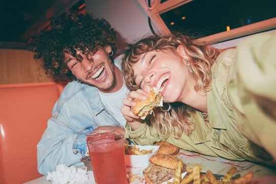 Friends eating burgers in a diner, a natural moment with glossy surfaces and bright colors for fast food and youth lifestyle marketing