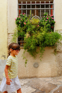 Young Girl Wearing Sunglasses Walking Through Historic Street in Altamura, Apulia, Italy