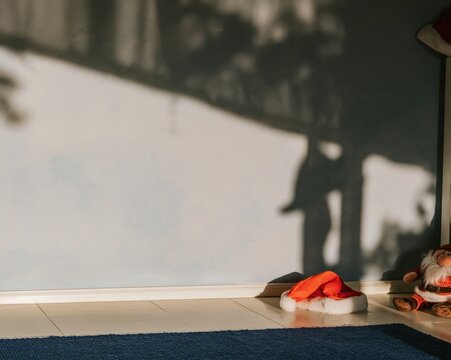 Periwinkle blue limewash wall with soft shadows, featuring a red santa hat and plush toy on a navy rug for a cozy christmas morning mockup