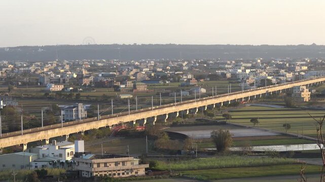 A wide view of a long elevated railway bridge spanning rural fields.