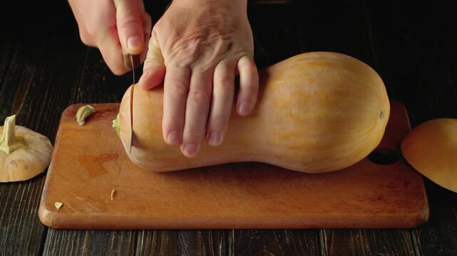Hand slicing butternut squash on wooden cutting board, with visible skin being removed, showcasing the continuous action of preparation in a kitchen setting with rustic elements
