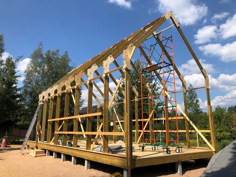 Construction of a timber frame barn style house with a gable roof, in the early stages of construction