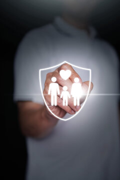 Finger touching glowing family shield hologram with heart icon, representing life insurance activation, health coverage policy, family protection, and personal safety security. Vertical stock photo.