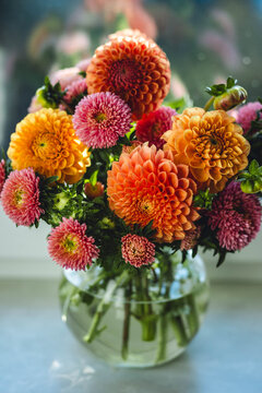 Elegant bouquet of beautiful bright colourful dahlias in a glass vase. Autumn mood, fall vibes
