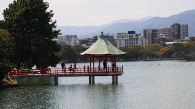 Ohori Park panorama in Fukuoka, Japan, Chuo-ku ward, Kyushu island, with pond, Ukimi-do pavilion, bridges and city skyline near Maizuru Park, lake and promenade in a spring sunny day