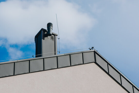 Modern Building Roof with Chimney Vent and Lightning Protection Against Blue Sky